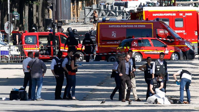 La police criminelle inspecte les lieux de l'attentat, lundi sur les Champs-Élysées, et recouvre le corps de l'assaillant.