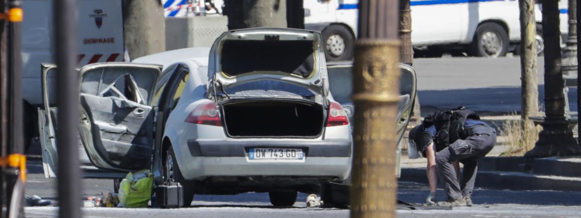 Un agent des forces de l'ordre se trouve à proximité de la voiture avec laquelle un homme a percuté un fourgon de gendarmerie, sur les Champs-Elysées, à Paris, le 19 juin 2017. (THOMAS SAMSON / AFP)